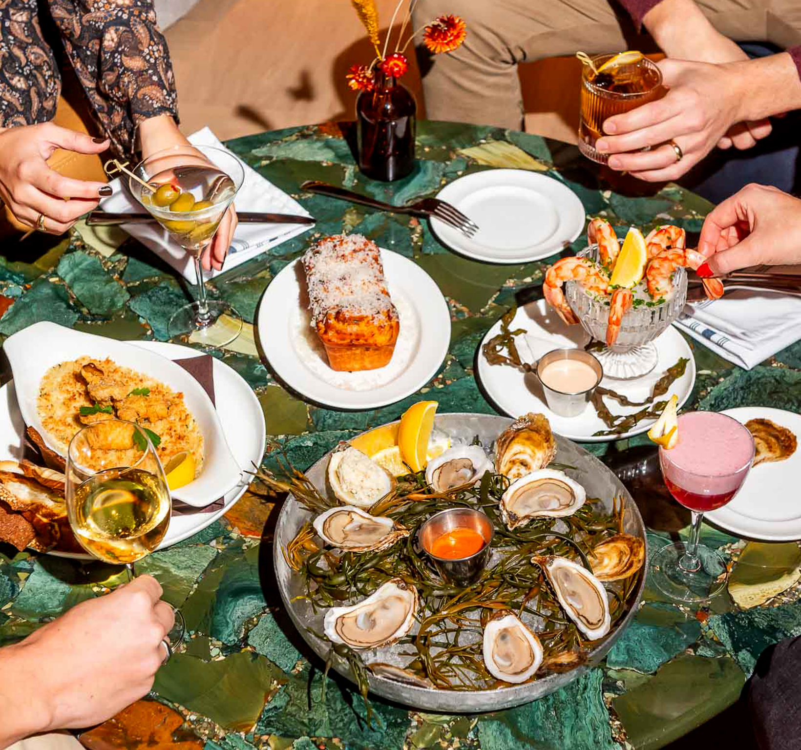 Table of bar bites with hands reaching into the frame at The Joneses restaurant in Toronto